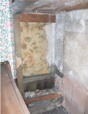 Inside of cupboard showing patch of old wallpaper.