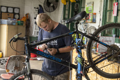 In image of Blake fixing a bike at the Cycle Hub